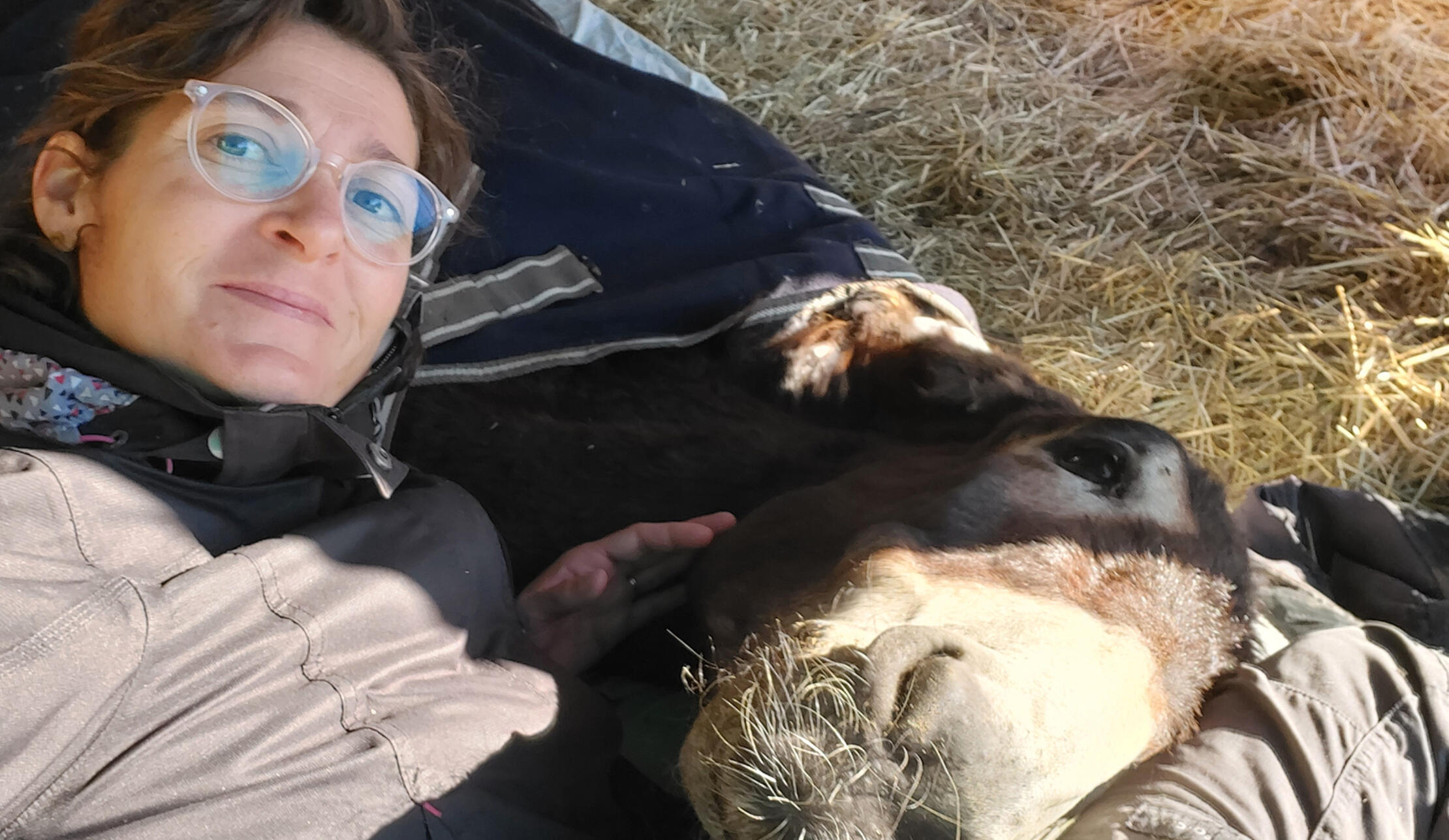Manou et l'âne Miro sont allongés entrelacés : la tête de Miro sur les genoux de Manou.